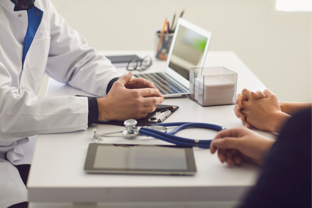 Confident Doctor and Couple Patient Sitting at the Table in Clinic Office Family Doctor